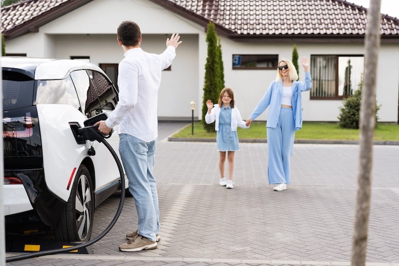 family-at-home-waving-to-man-charging-car-2026-01-08-22-54-51-utc